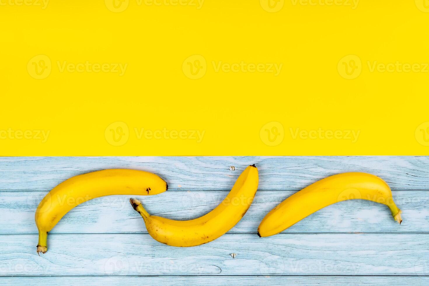 gul bananer lögn på en blå trä- bakgrund och en gul bakgrund foto