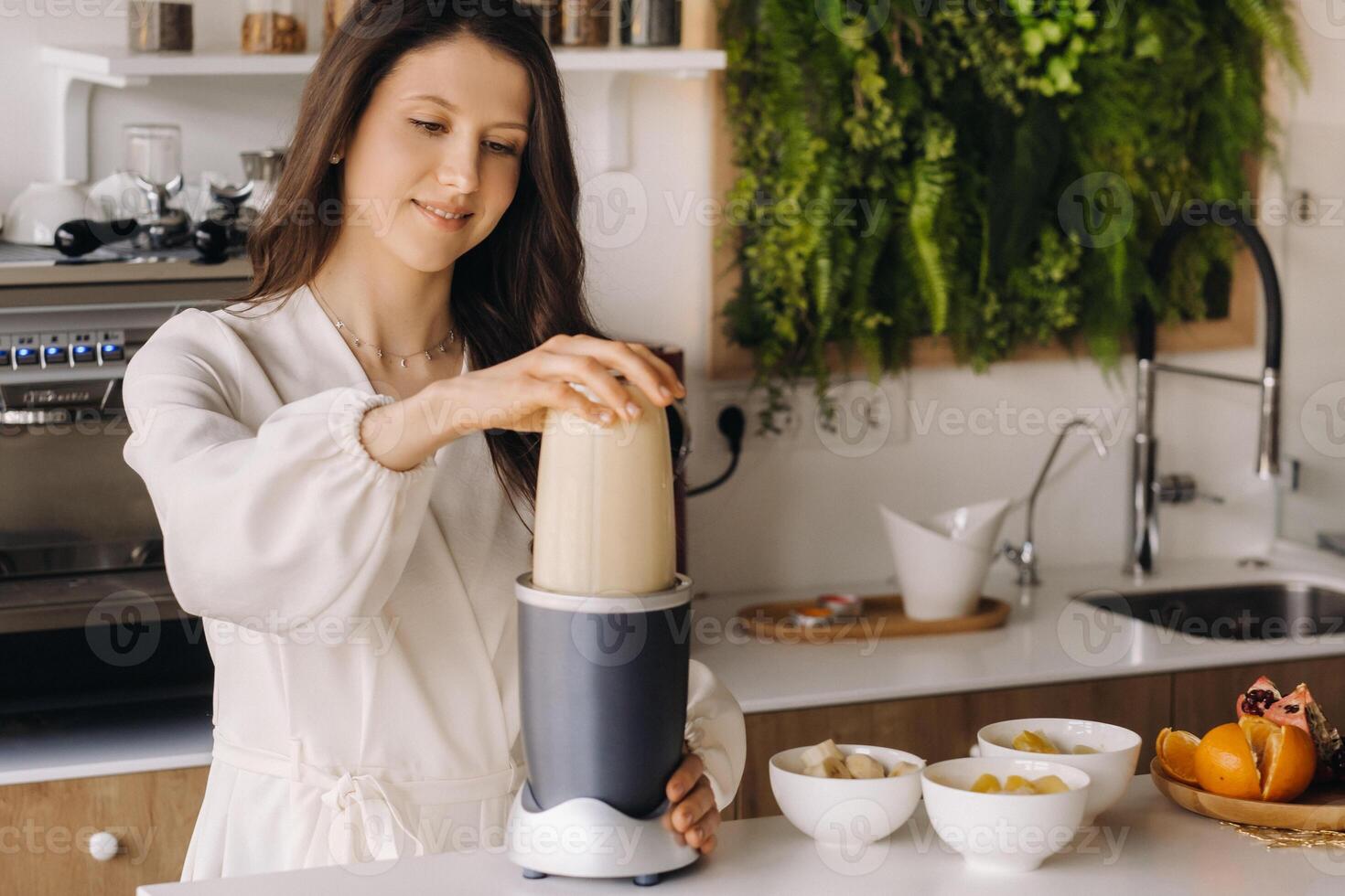 en flicka gör en cocktail i en frukt blandare i de kök. diet för vikt förlust foto