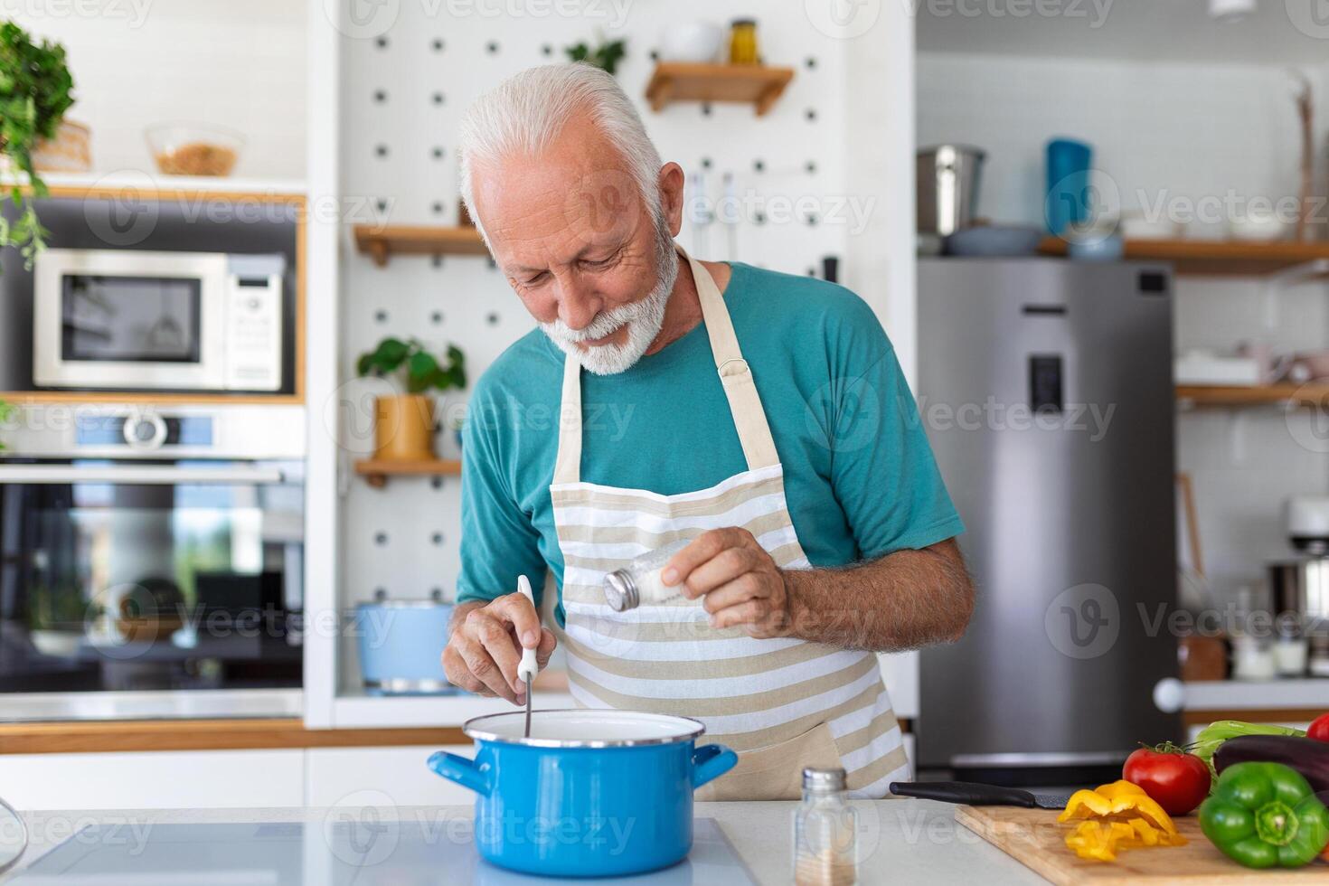 Lycklig senior man har roligt matlagning på Hem - äldre person framställning hälsa lunch i modern kök - pensionerad livsstil tid och mat näring begrepp foto