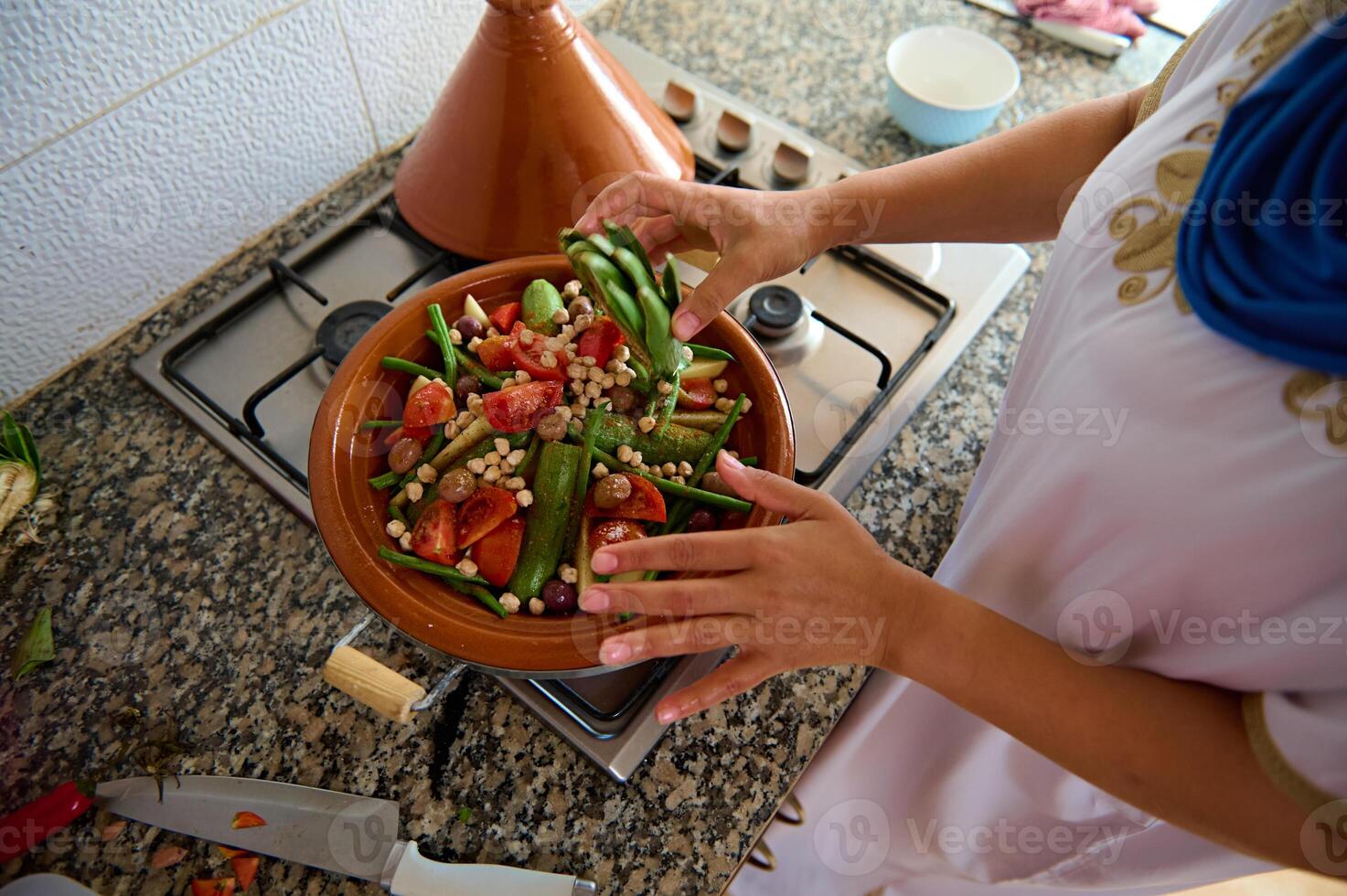 topp se hemmafru stapling grönsaker i lera maträtt, framställning utsökt hemlagad marockansk tagine i de Hem kök foto