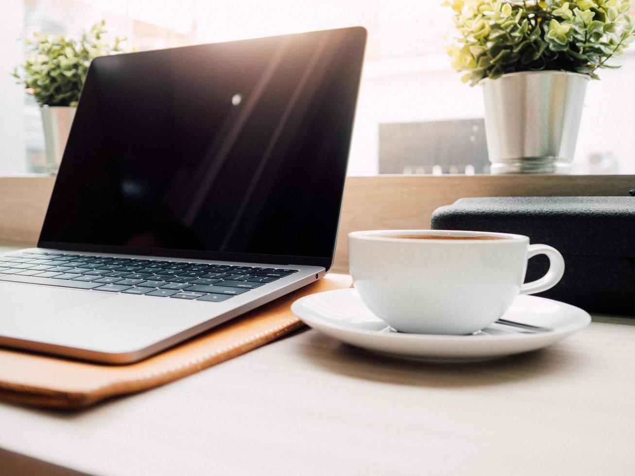 laptop och en kopp kaffe med morgonljus i caféet. foto