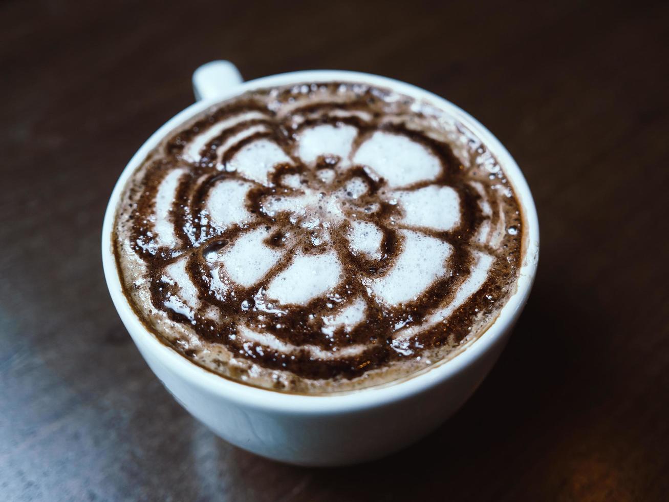 varmt kaffe i vit kopp på mörkt träbord. foto