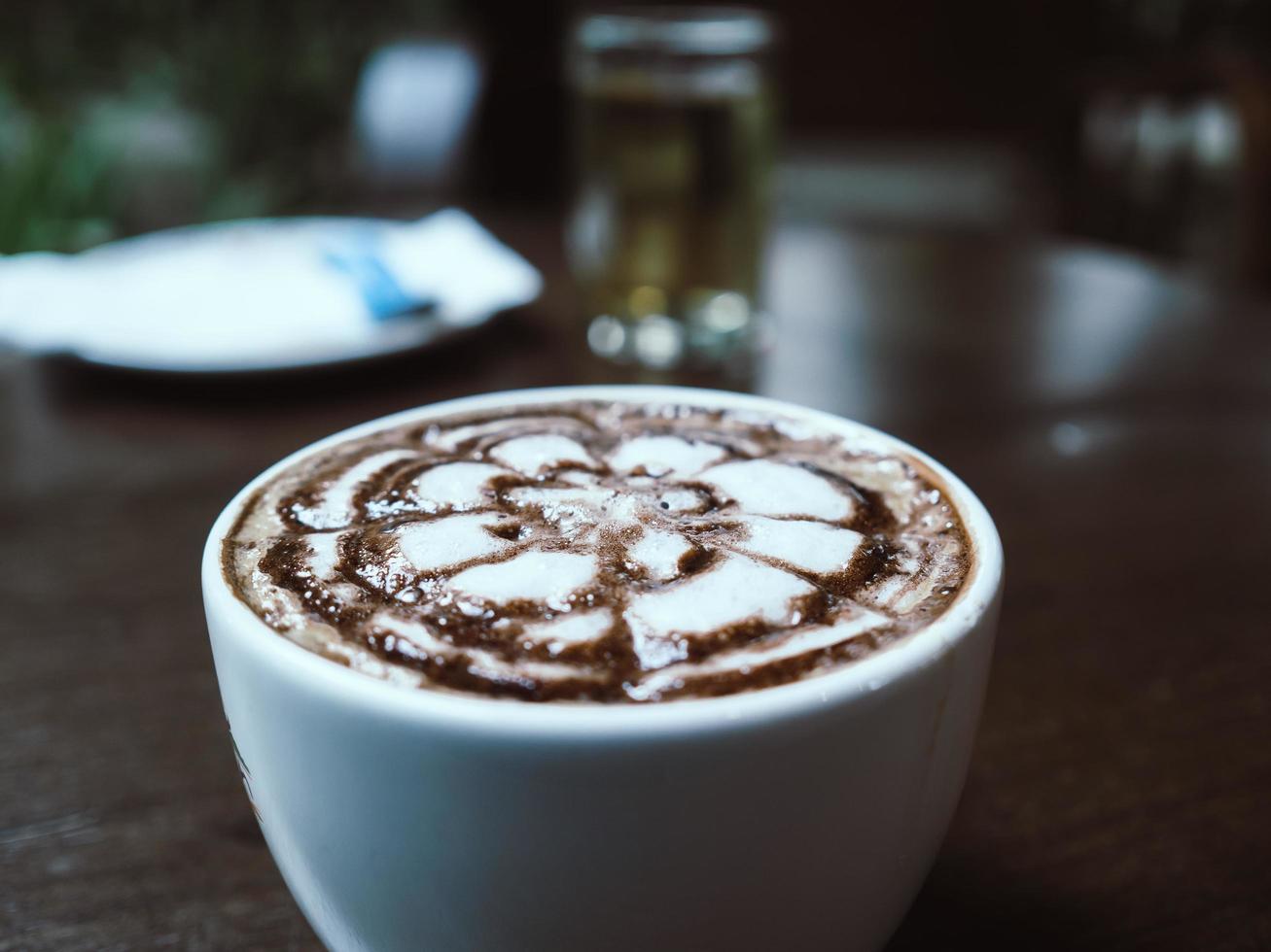 varmt kaffe i vit kopp på mörkt träbord. foto