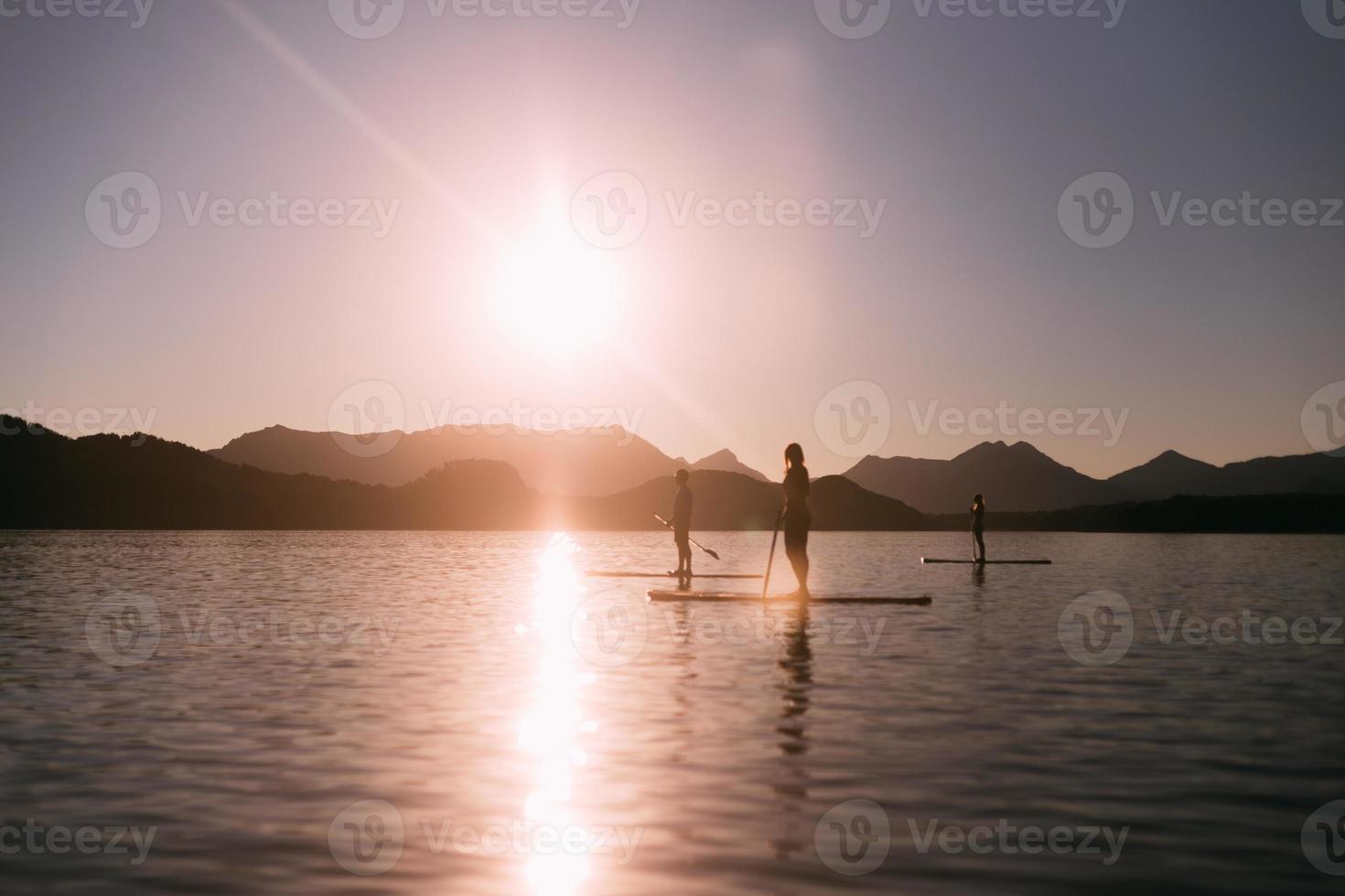 stå upp paddla vid solnedgången foto