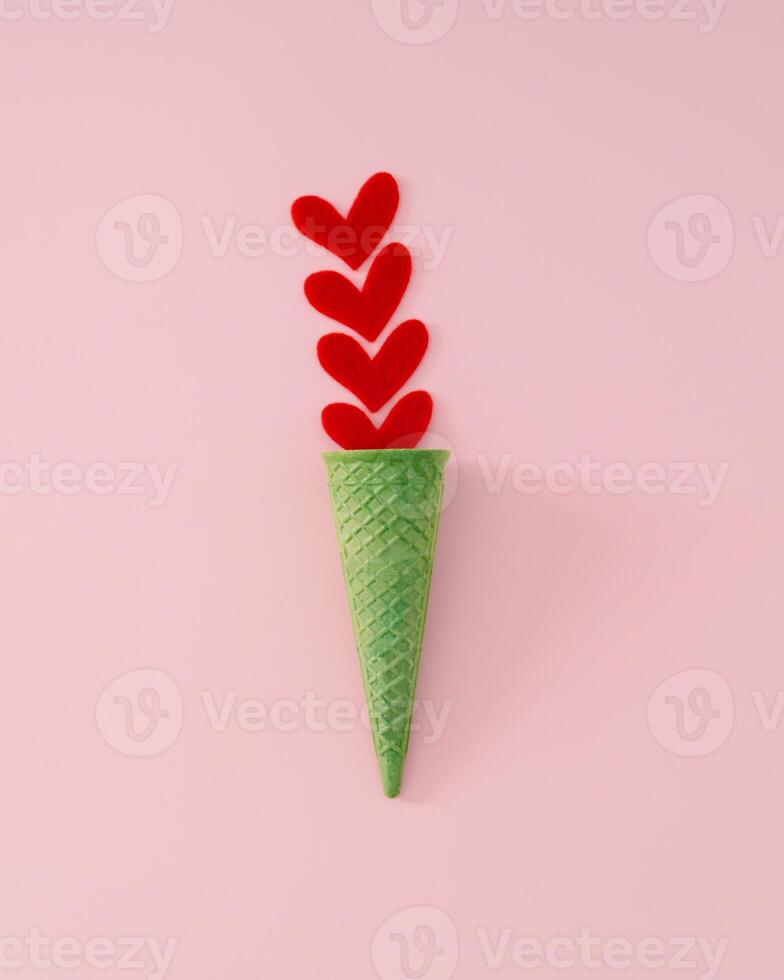 sommar kärlek grädde. kreativ layout tillverkad med röd hjärtan och grön våffla is grädde kon på rosa bakgrund. minimal sommartid kärlek begrepp. romantisk is grädde aning. platt lägga. foto