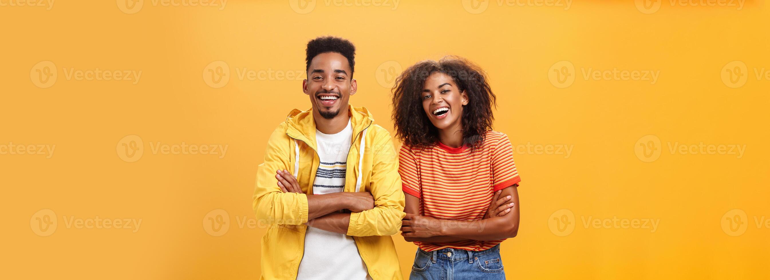 två afrikansk amerikan man och kvinna varelse bäst vänner skrattande ut högt tittar på rolig film i bio Allt klädd upp i eleganta utrusta stående med händer korsade på bröst och roade uttryck foto