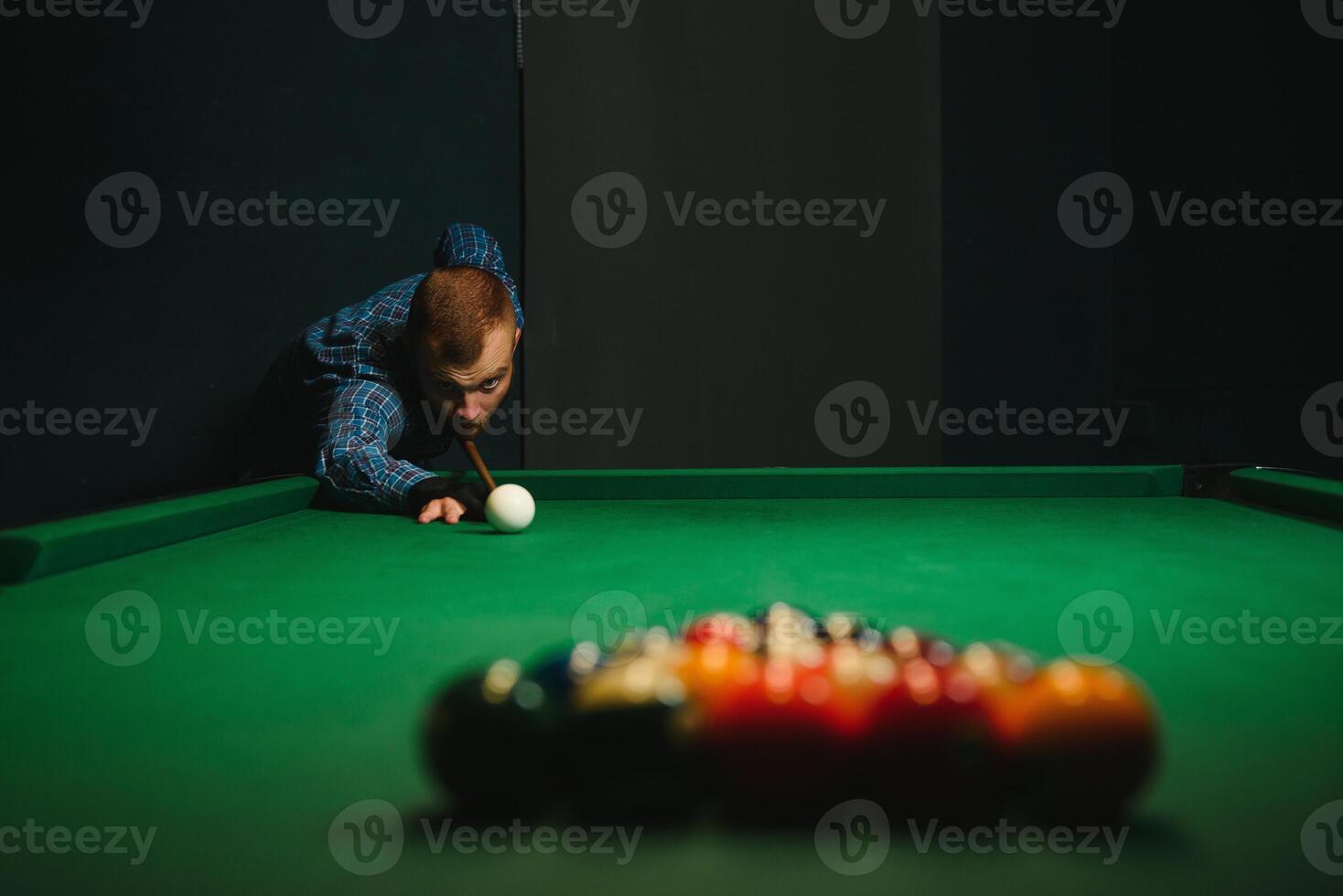 ung stilig man lutande över de tabell medan spelar snooker foto