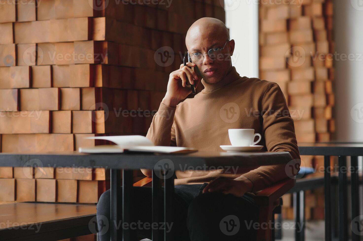 koncentrerad svart manlig entreprenör läser papper dokument Sammanträde i Kafé med kaffe nära fönster. foto