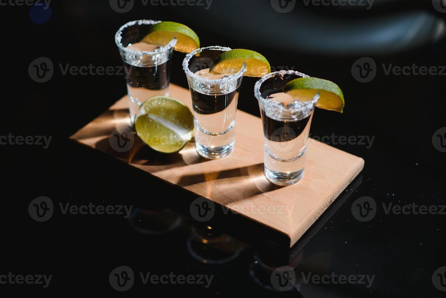 tequila med kalk och salt på svart bakgrund foto