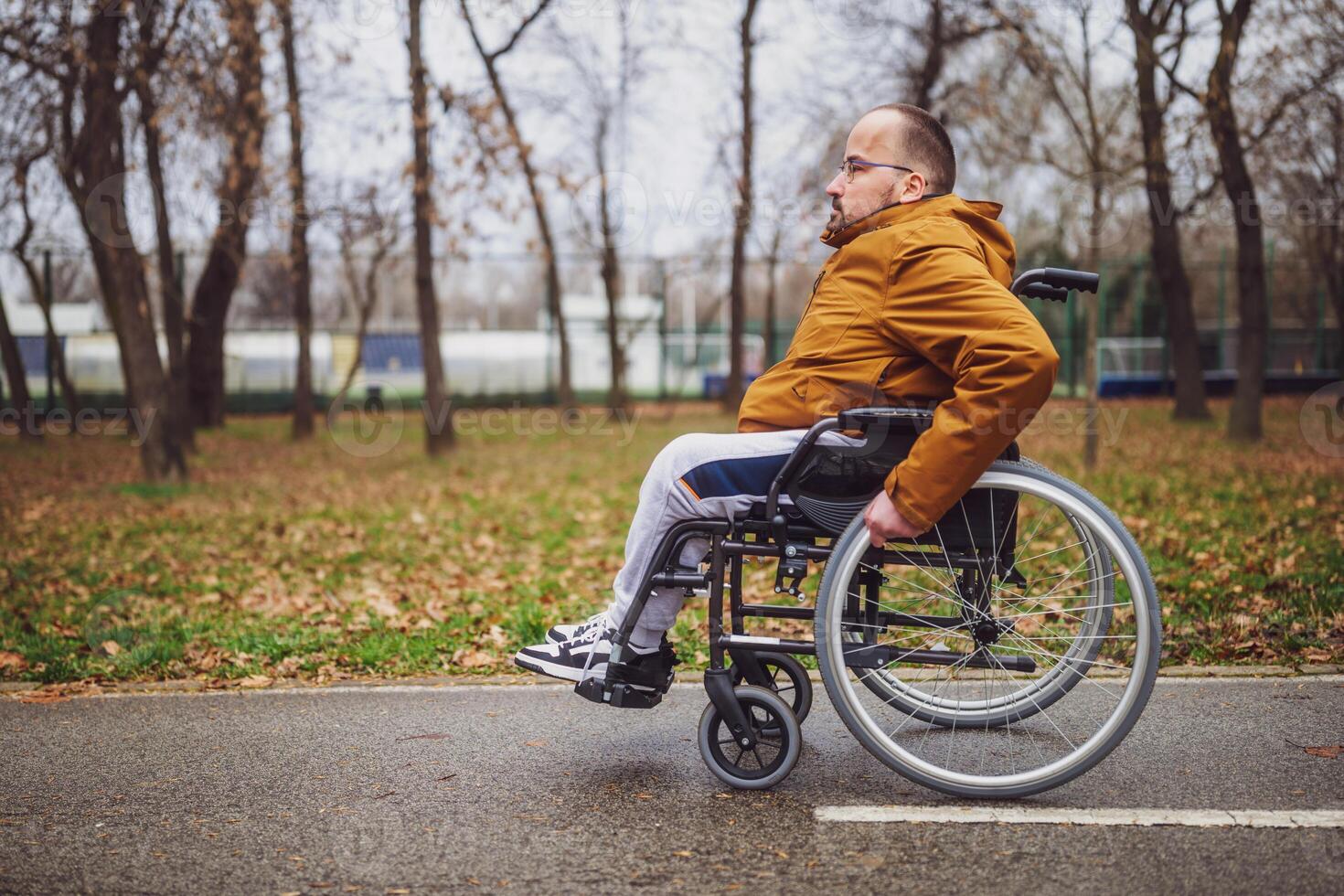 porträtt av paraplegic handikappade man i rullstol i parkera. han är rullande på väg. foto