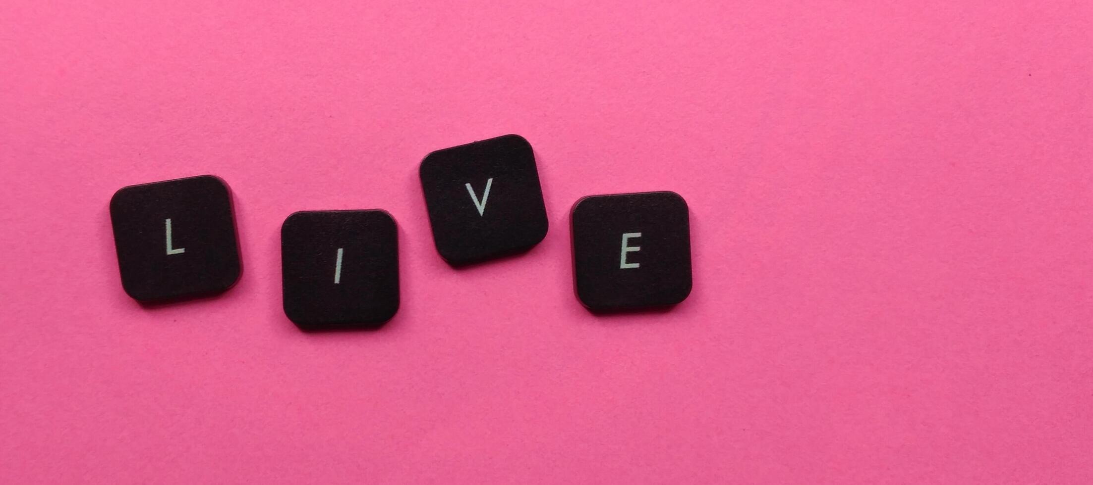 leva ord tillverkad av svart kuber på rosa bakgrund, topp se. foto