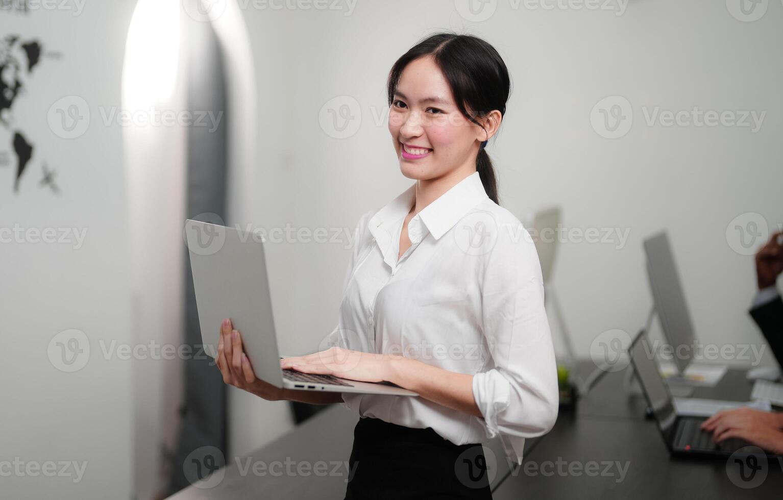 leende affärskvinna använder sig av en bärbar dator på de kontor. foto