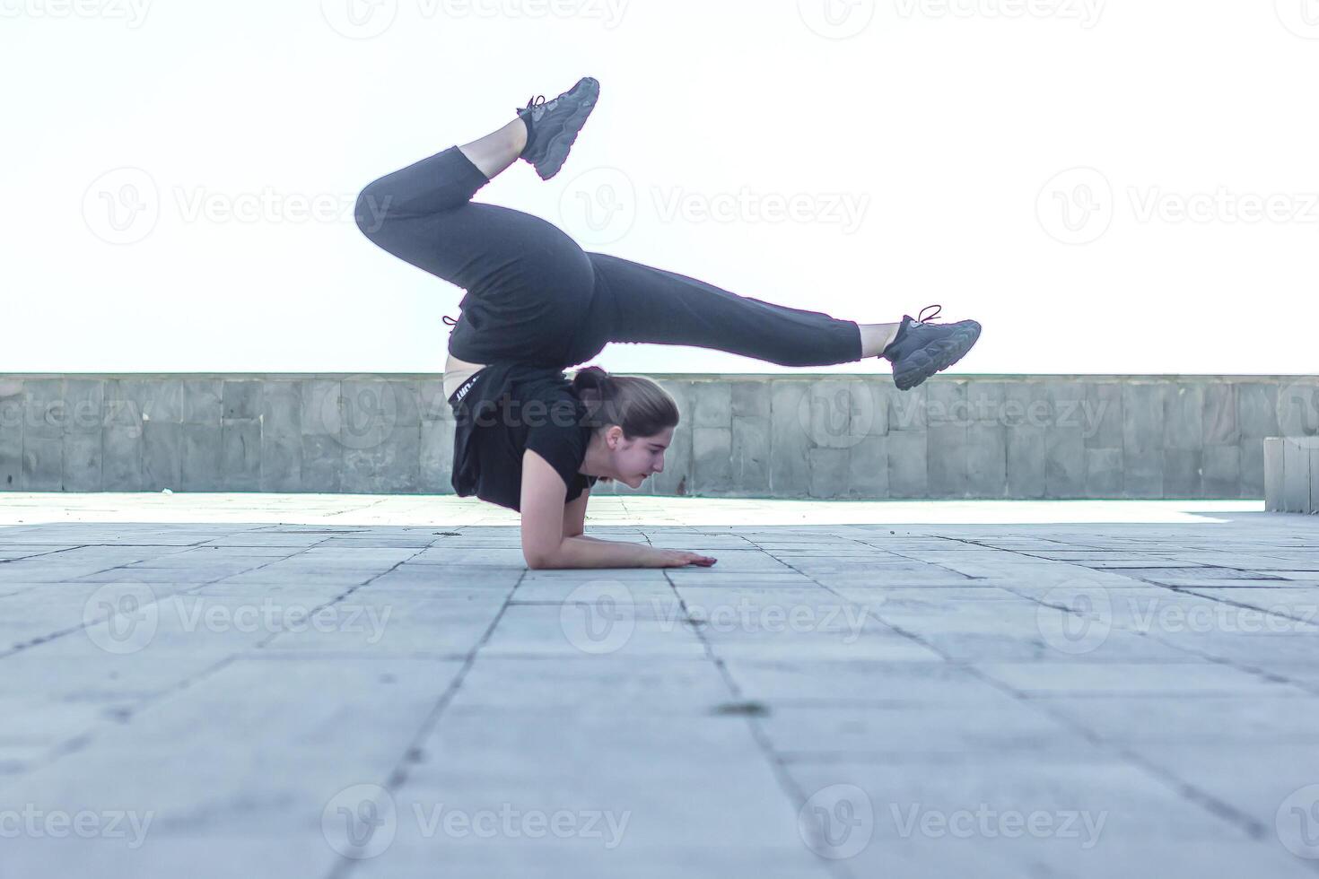 ung flicka håller på med övning i de stad, kvinna håller på med yoga träning, person håller på med stretching, kvinna avkopplande i de stad, Söt flicka håller på med kondition övning foto