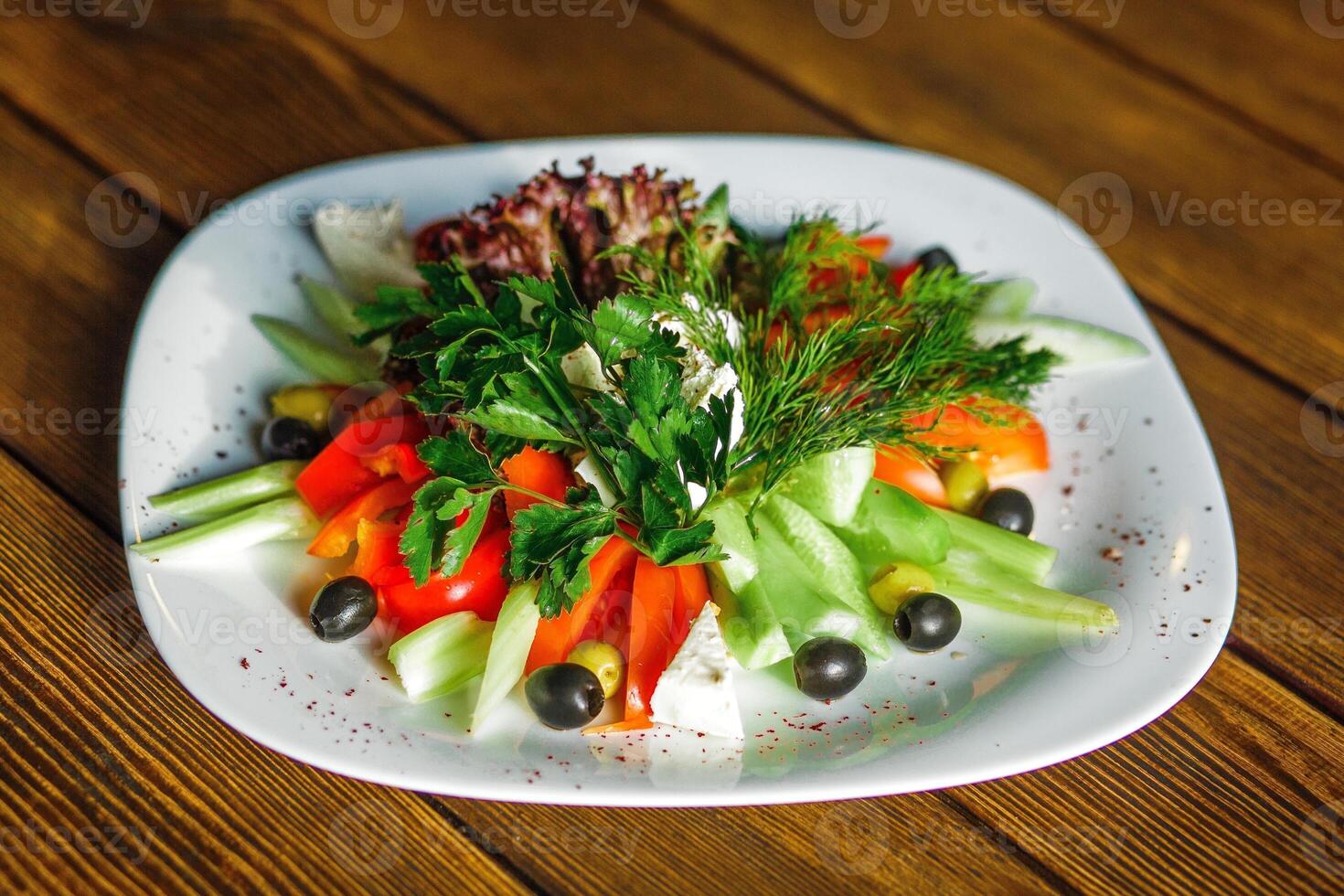 grekisk sallad med färsk grönsaker och fetaost ost på en trä- tabell foto