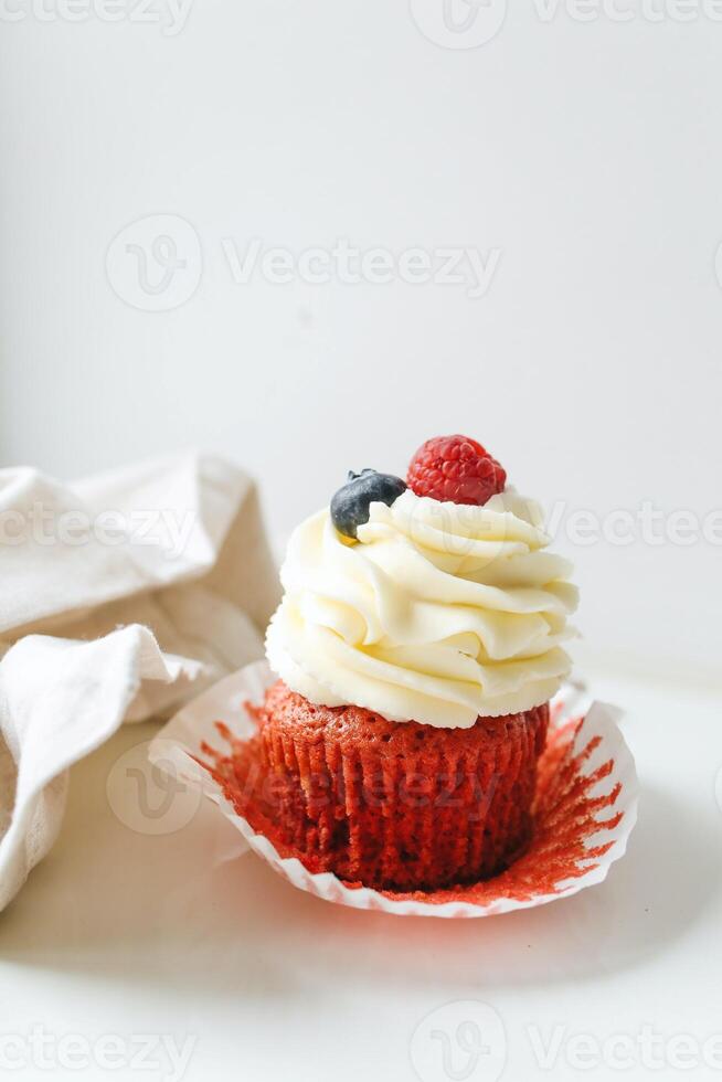 röd sammet muffin med färsk hallon och blåbär på vit bakgrund foto