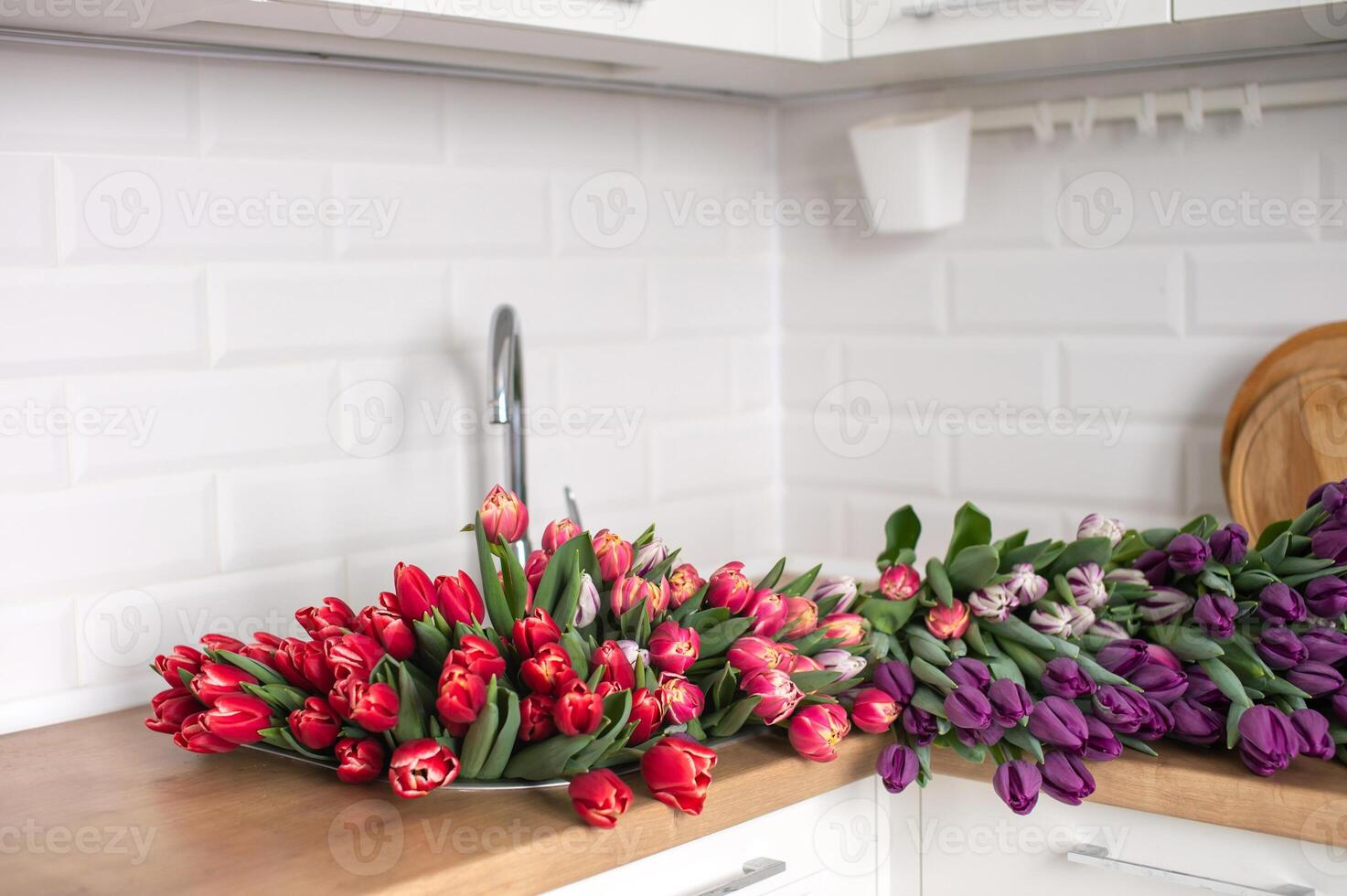 en stor siffra av tulpaner av annorlunda färger lögner på de tabell i de kök. blommor i de handfat foto