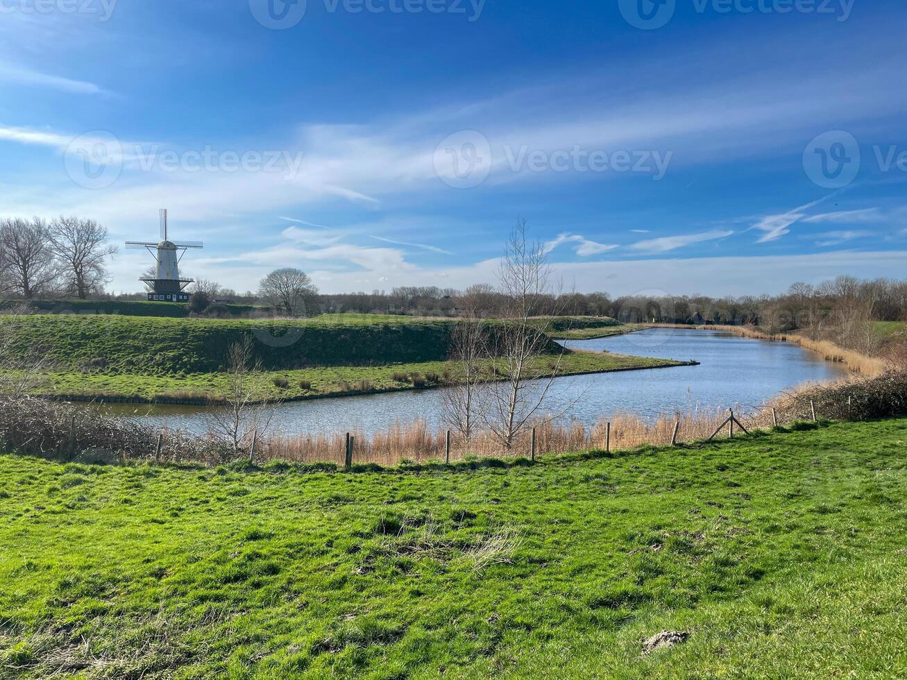 landskap med kanal och väderkvarn i de nederländerna foto