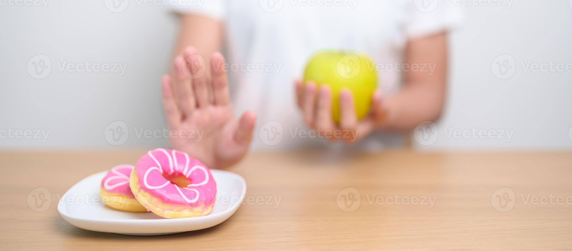 kvinna hand håll grön äpple och avvisa munk, kvinna kondition välja mellan frukt är friska och ljuv är ohälsosam skräp mat. bantning kontrollera, vikt förlust, fetma, äter livsstil och näring foto