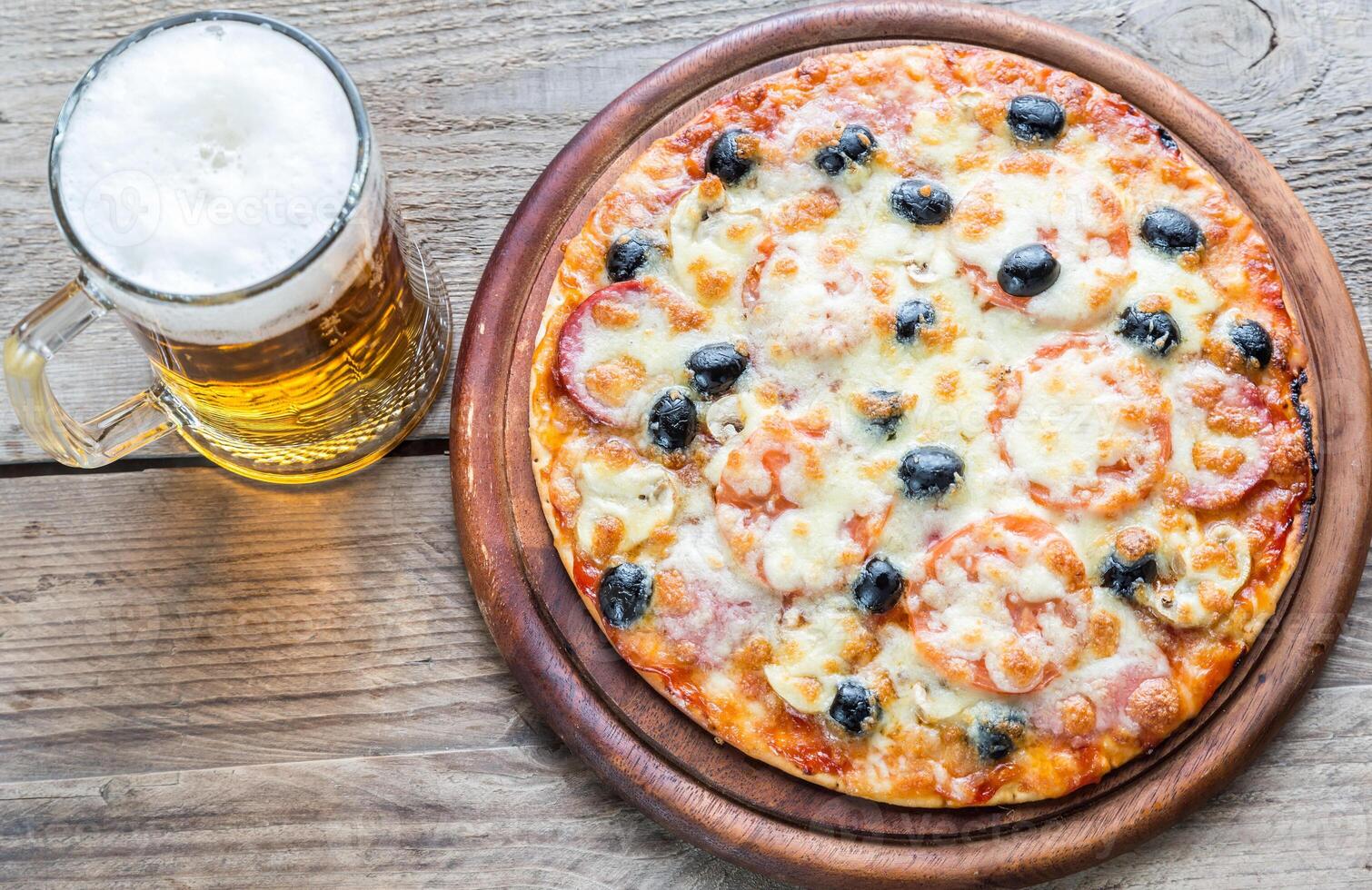 kokta pizza med en glas av öl foto