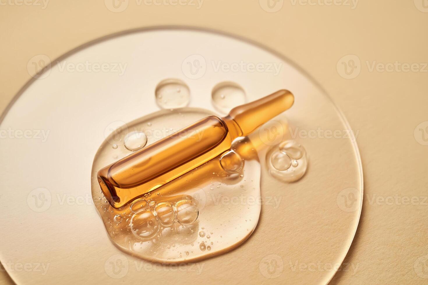 ampull i en släppa av kosmetisk gel på en beige bakgrund. foto