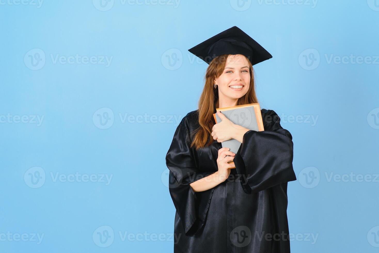 skön kvinna bär gradering keps och ceremoni morgonrock innehav grad ser positiv och Lycklig stående och leende med en självsäker leende. foto