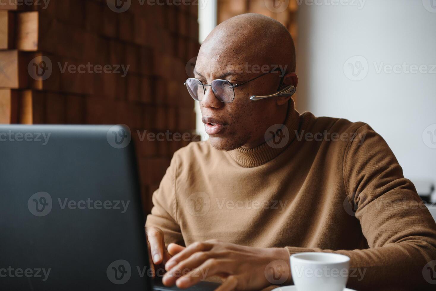 fokuserade afrikansk man bär hörlurar tittar på webinar Träning framställning anteckningar studie uppkopplad inlärning språk på dator, svart manlig studerande ser på bärbar dator elearning i internet skriva information. foto