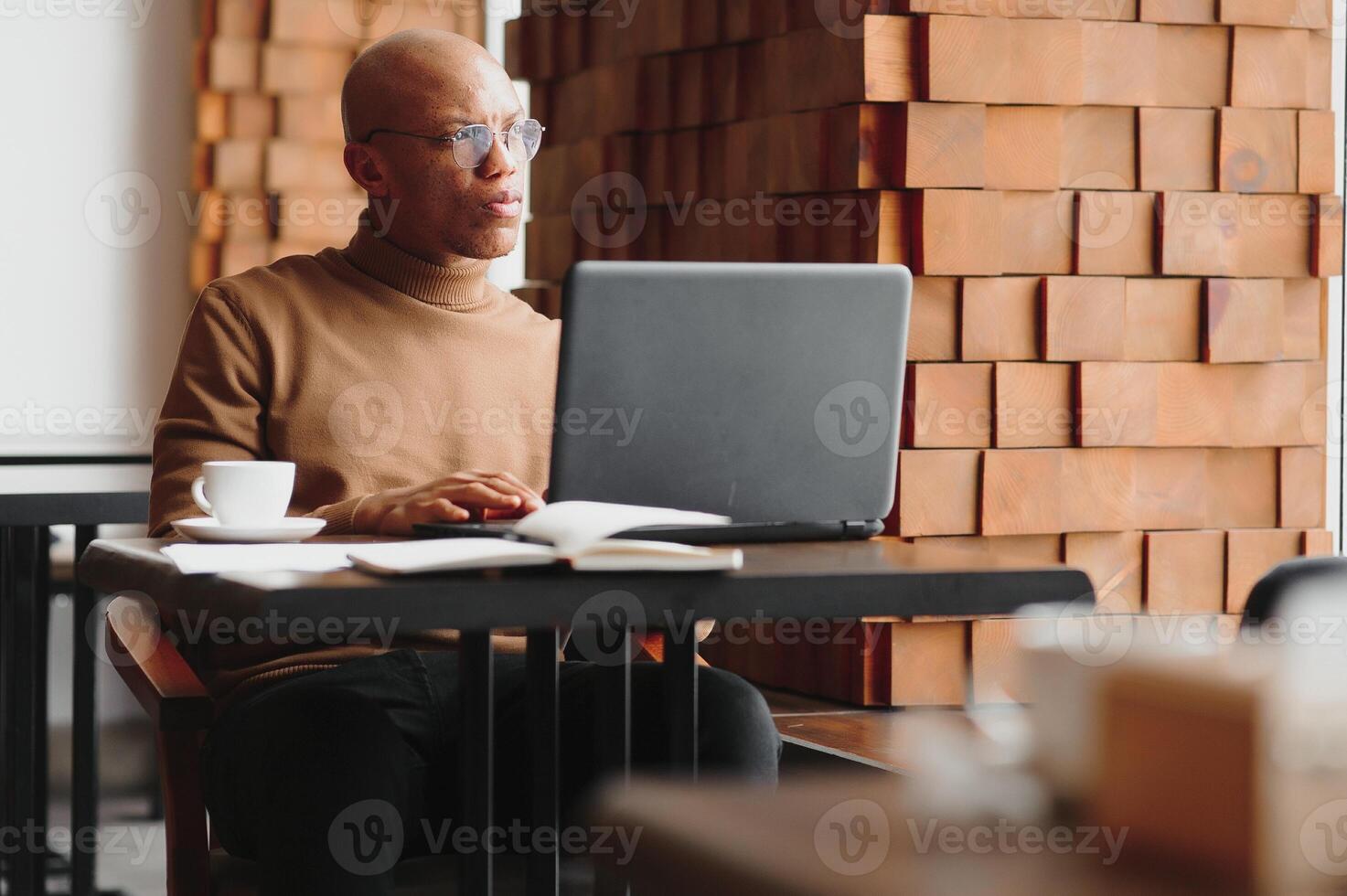 kunskap, inlärning, utbildning och teknologi. vardagligt klädd hårt arbete en student med afro frisyr lösning matematisk problem, Sammanträde på Kafé tabell med läroböcker och elektronisk enhet. foto