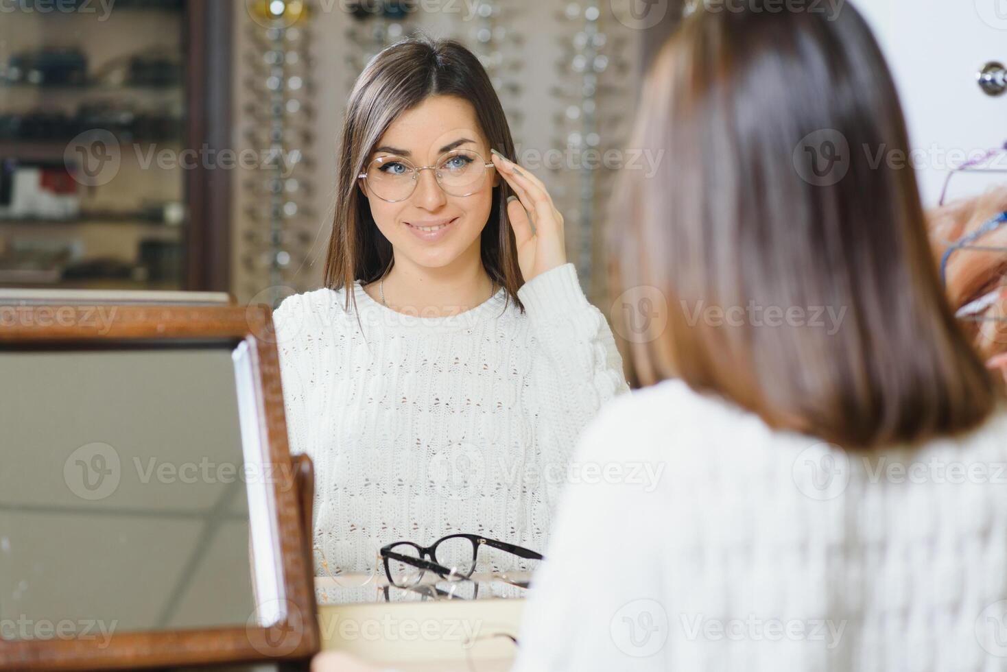 flicka handla för glasögon på försäljning säsong i optisk Lagra. eleganta kund uppköp många glasögon på rabatt. foto