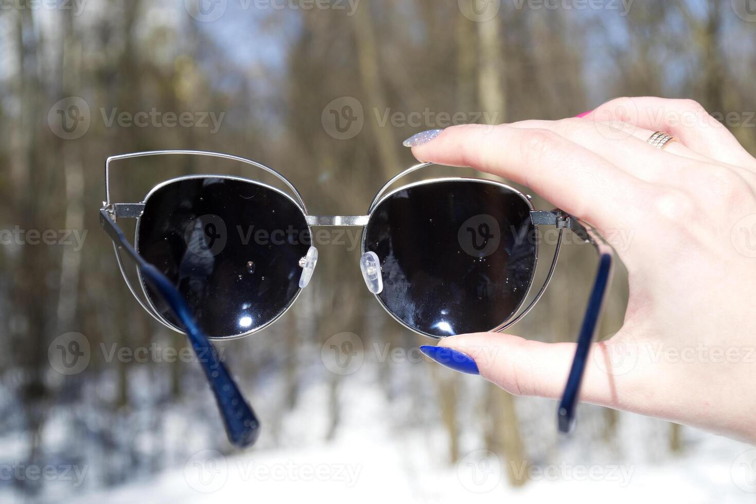 solglasögon i kvinna hand. makro skott i en skog. foto