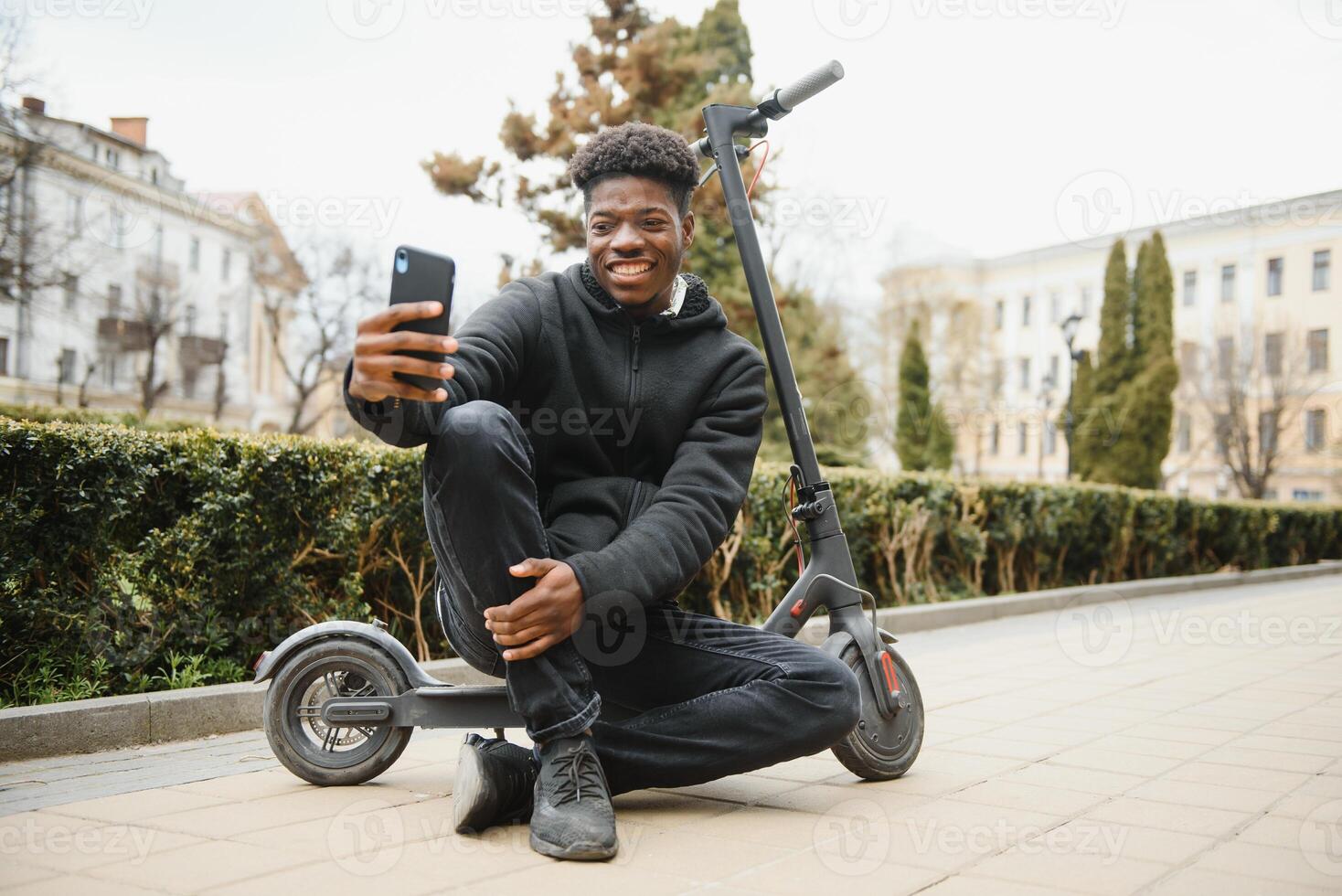 full kropp sida porträtt Lycklig afrikansk amerikan man på mobil skoter på gata foto