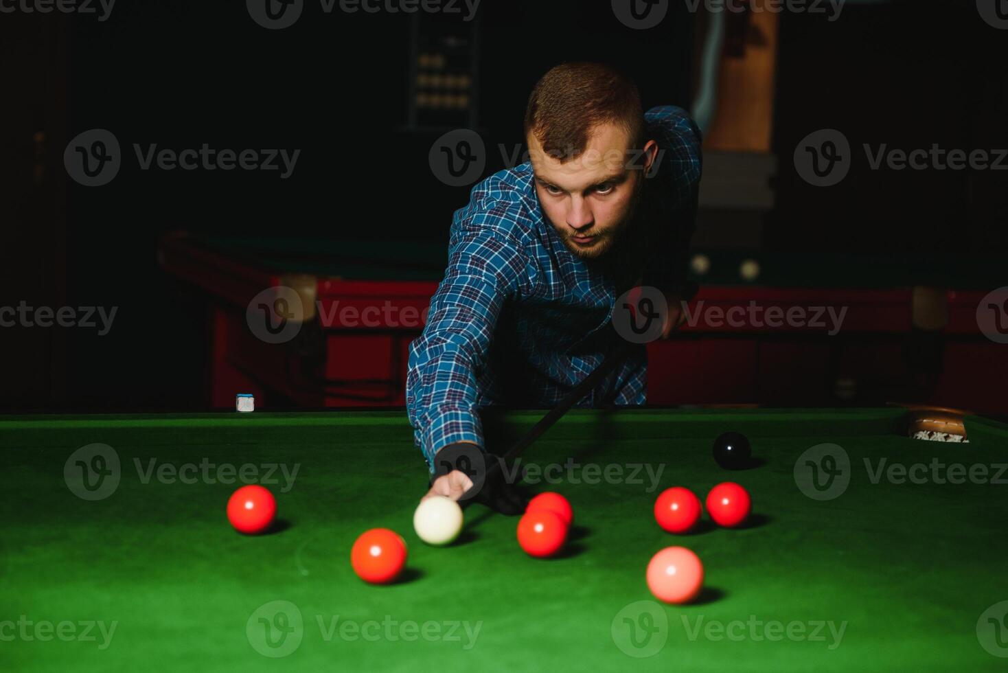 ung stilig man lutande över de tabell medan spelar snooker foto