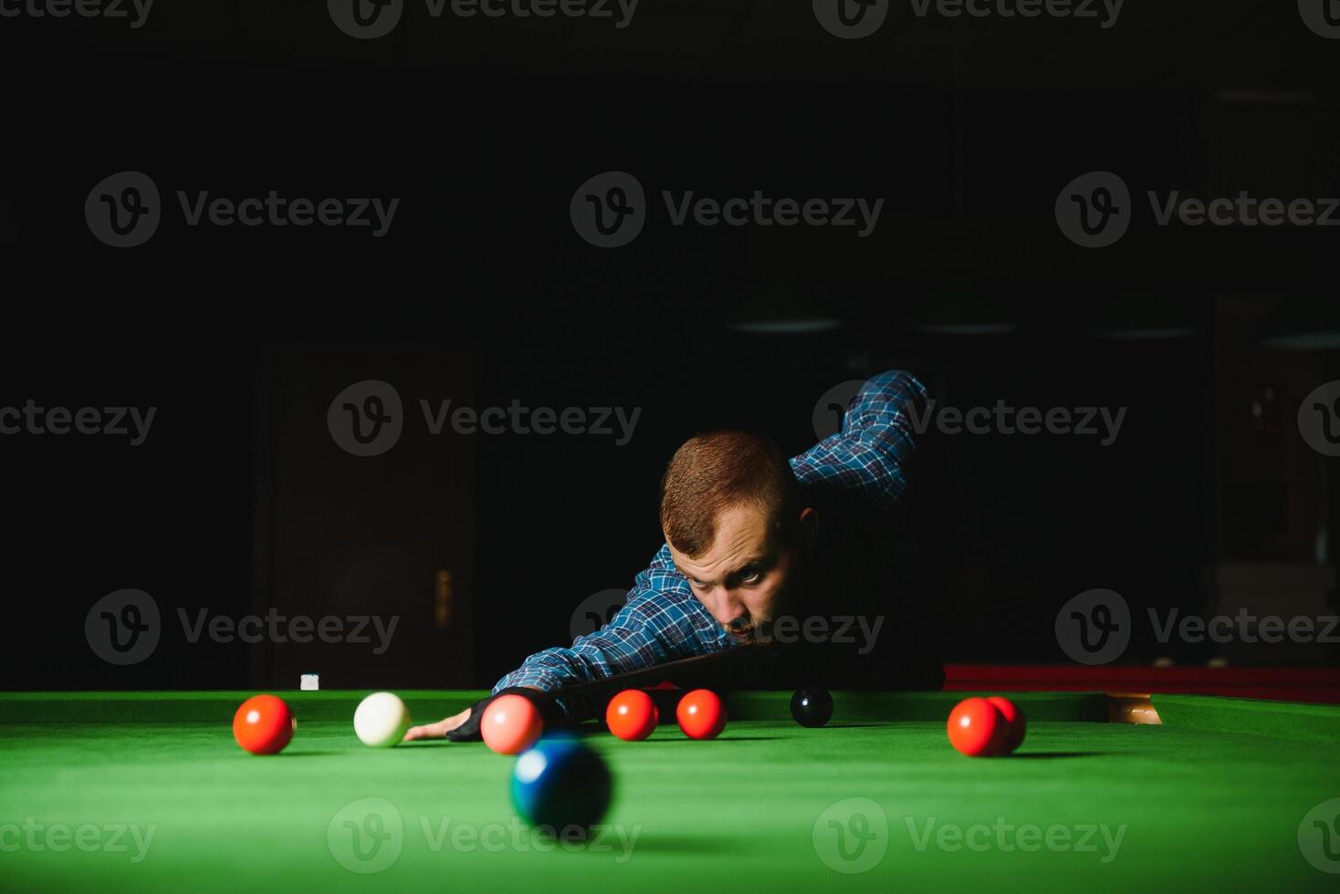 ung stilig man lutande över de tabell medan spelar snooker foto