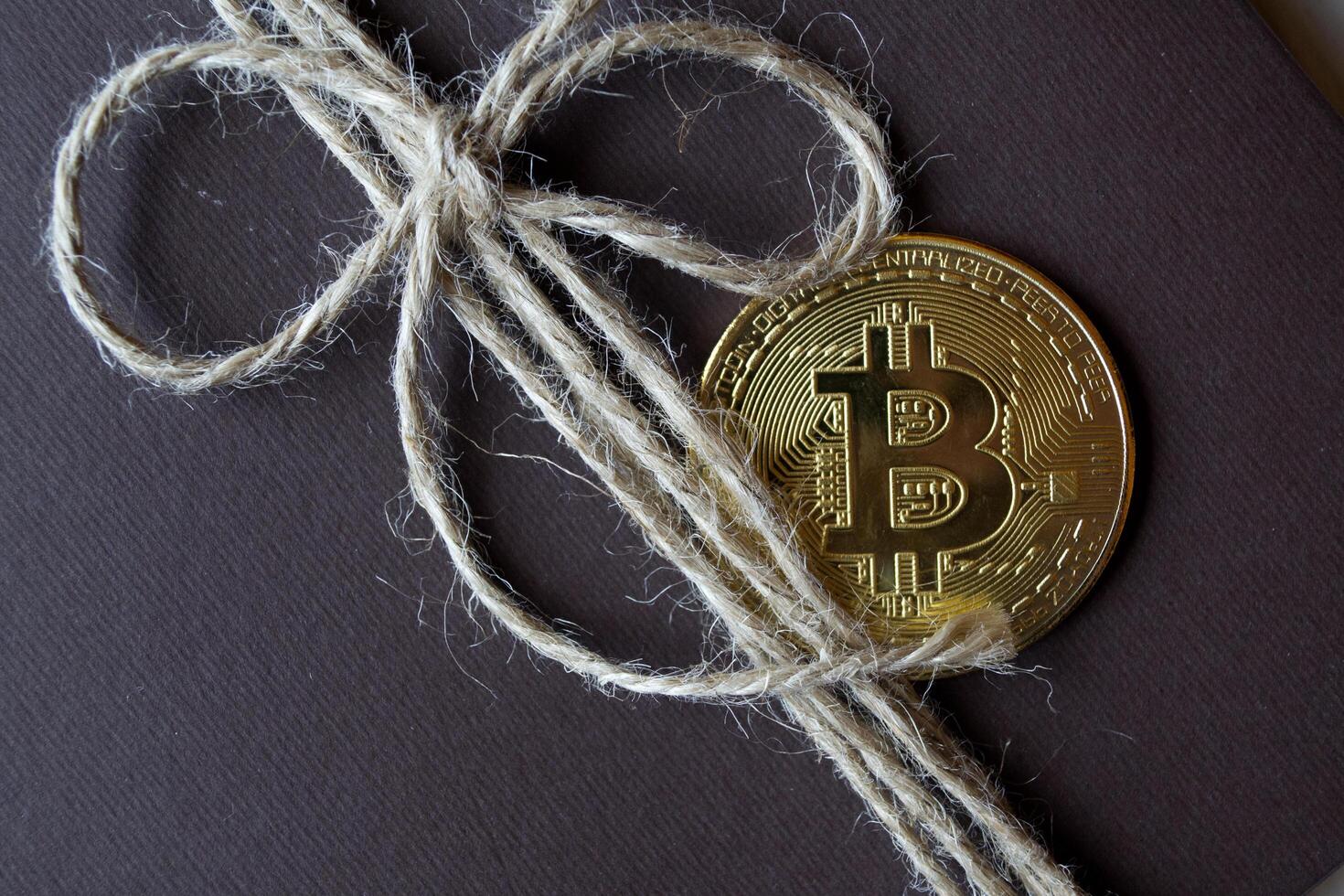 gyllene bitcoin på en brun gåva låda. en mynt av kryptovaluta. foto