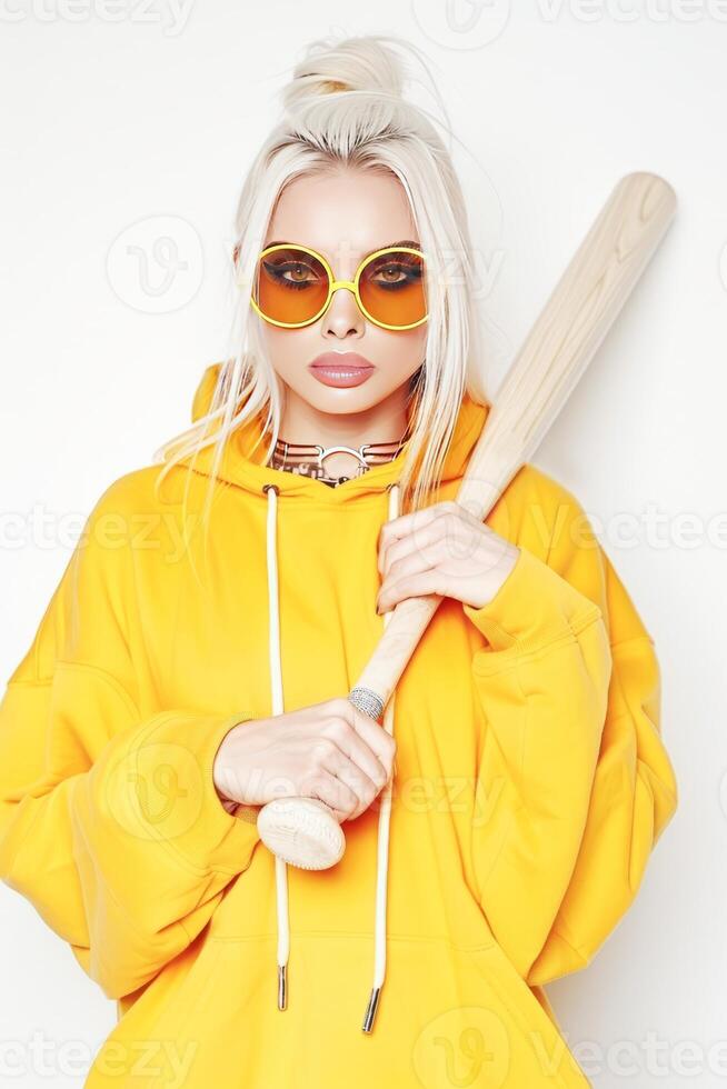 ai genererad modern ung kvinna i gul luvtröja innehav baseboll fladdermus mot vit bakgrund foto