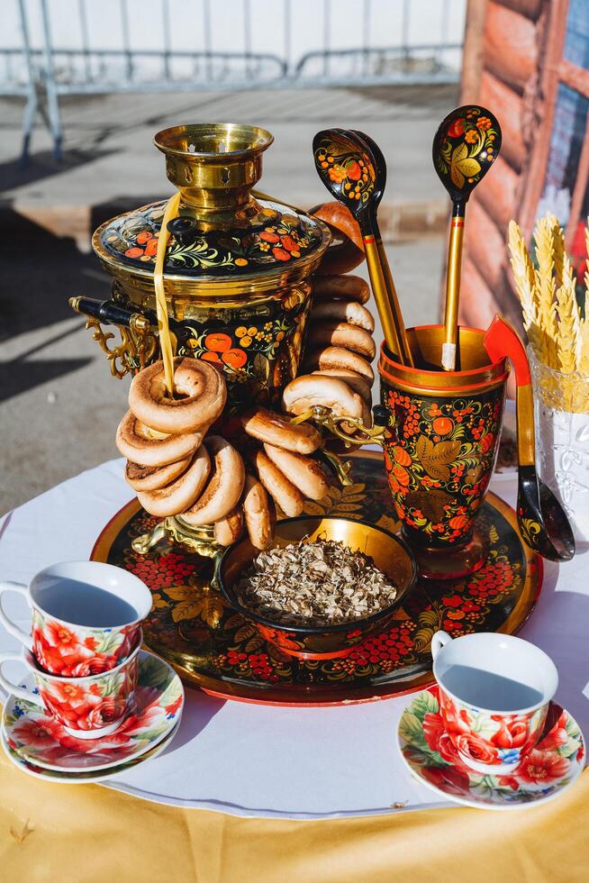 maträtter av de ryska människor målning i de stil av khokhloma, samovar med kokande vatten, lind te, bagels hängande på en rep, bagels, skedar i en glas. foto