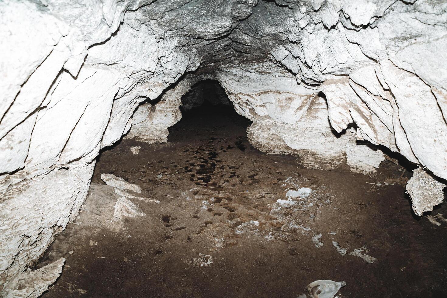 kalkhaltiga grotta, lera med vatten på de golv av de grotta textavsnitt, karst hål, mörk korridor underjordiska, speleologi. foto