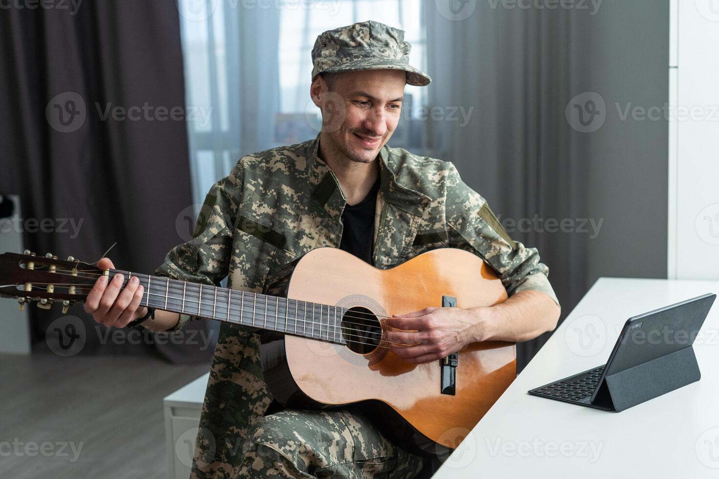 glad leende ung militär man bär kaki enhetlig innehav gitarr. foto