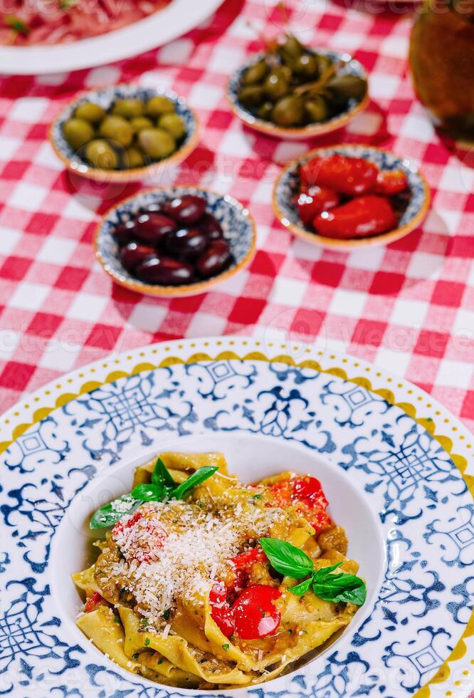 italiensk pasta med tomater, parmesan, basilika och oliver foto