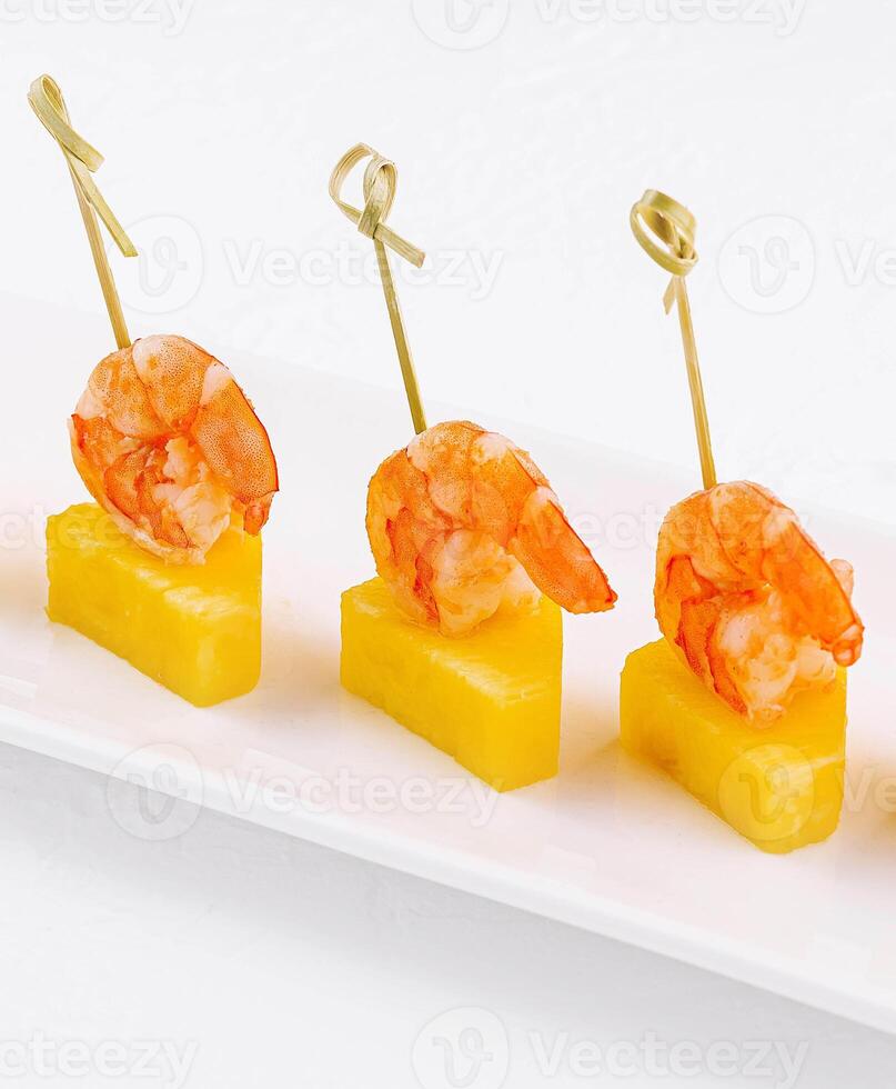 canapes med räka och ananas på tallrik foto