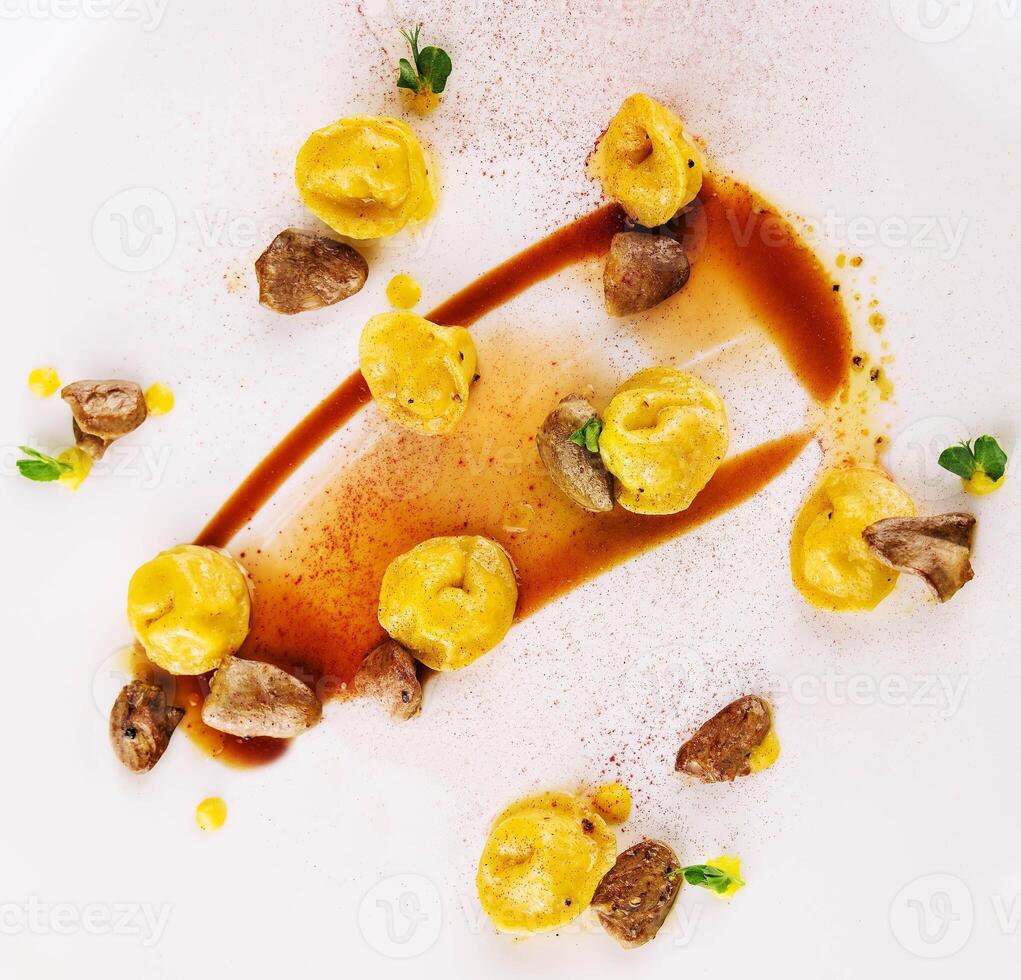 en tallrik av ravioli med friterad njurar och paprika topp se foto
