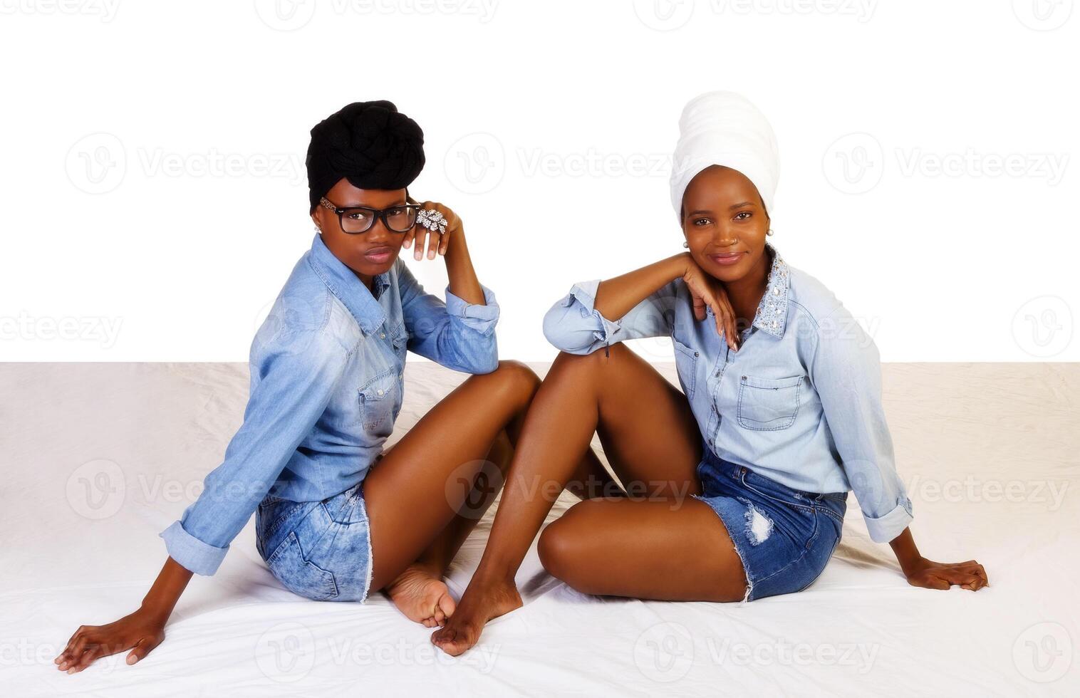 två svart systrar Sammanträde i jean shorts foto