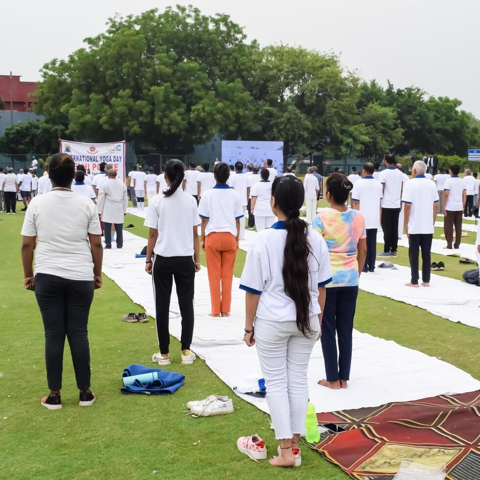 ny delhi, Indien, juni 21, 2023 - grupp yoga övning session för människor på yamuna sporter komplex i delhi på internationell yoga dag, stor grupp av vuxna delta yoga klass i cricket stadion foto