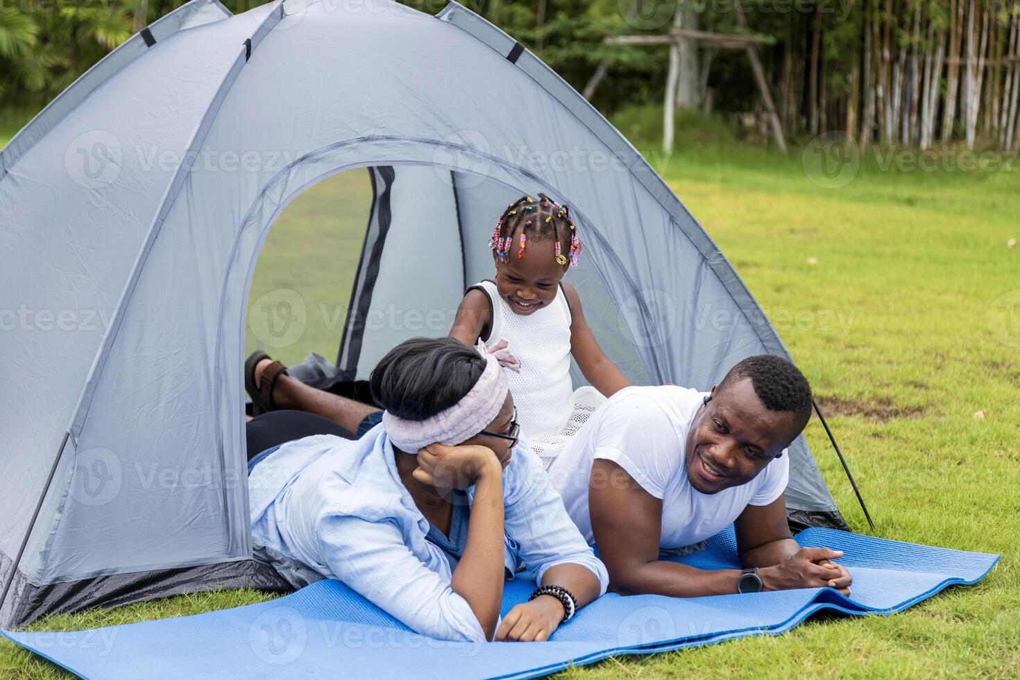 Lycklig afrikansk amerikan familj utgifterna tid tillsammans under semester på de camping tält utomhus- nationell parkera foto