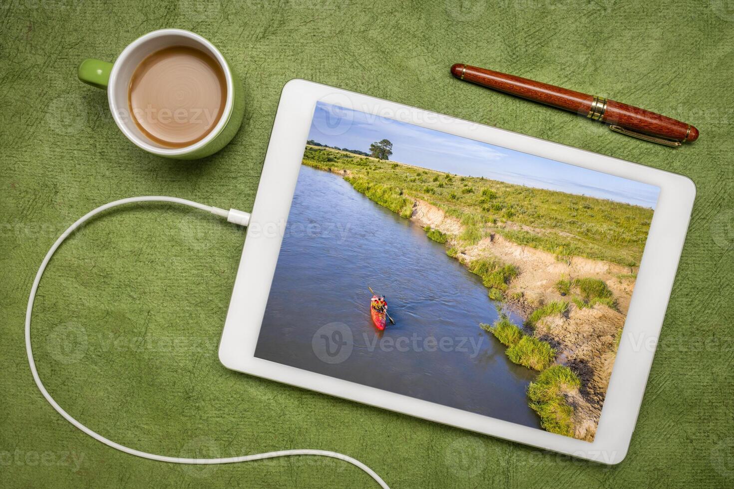 kayaker på en grund och bred dyster flod i Nebraska - granskning en semester bild på en digital läsplatta foto