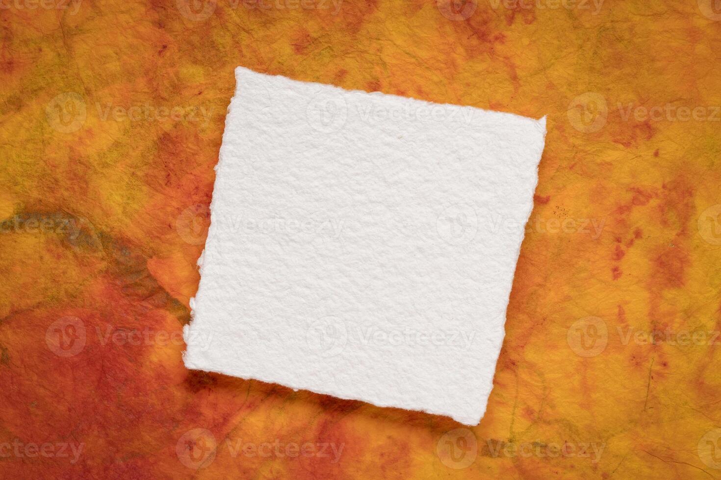 små fyrkant ark av tom vit khadi papper mot färgrik marmorerad papper foto