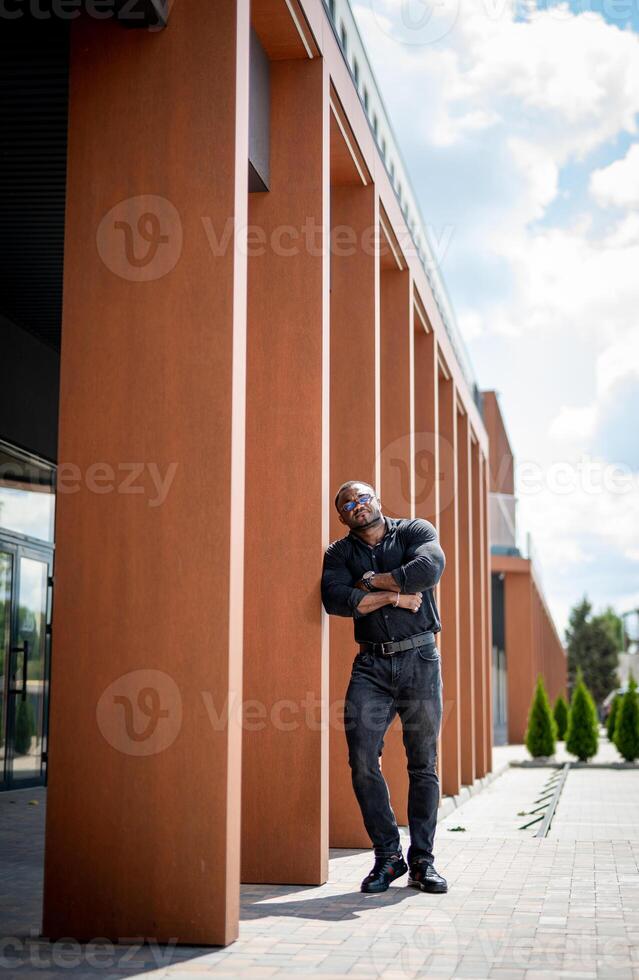 stilig affärsman i glasögon på modern stad gata. ung självsäker man i urban stad. foto