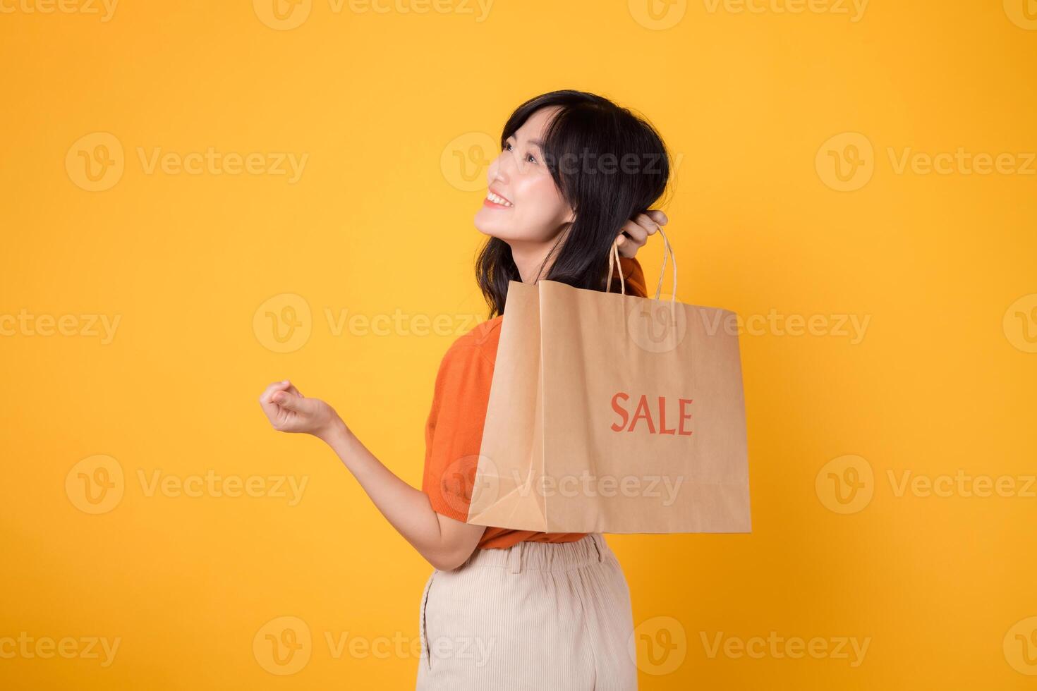 erfarenhet de spänning av upptäckt fynd i en trendig köpcenter miljö. leende asiatisk kvinna 30s ställer ut henne handla dra, reflekterande de glädje av smart köp. foto