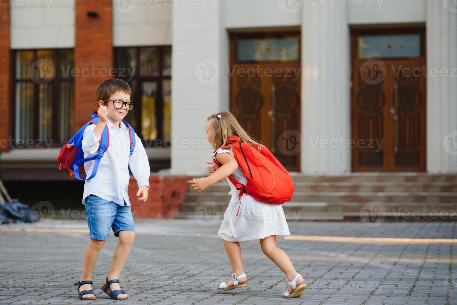 Lycklig barn gå tillbaka till skola. elev av primär skola gå studie med ryggsäck utomhus. barn gå hand i hand. början av lektioner. först dag av falla. pojke och flicka från elementärt studerande. foto