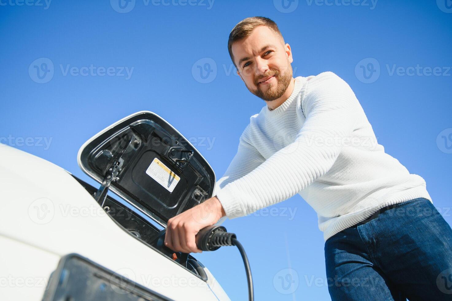 leende man proppborttagnings de laddare från de bil foto