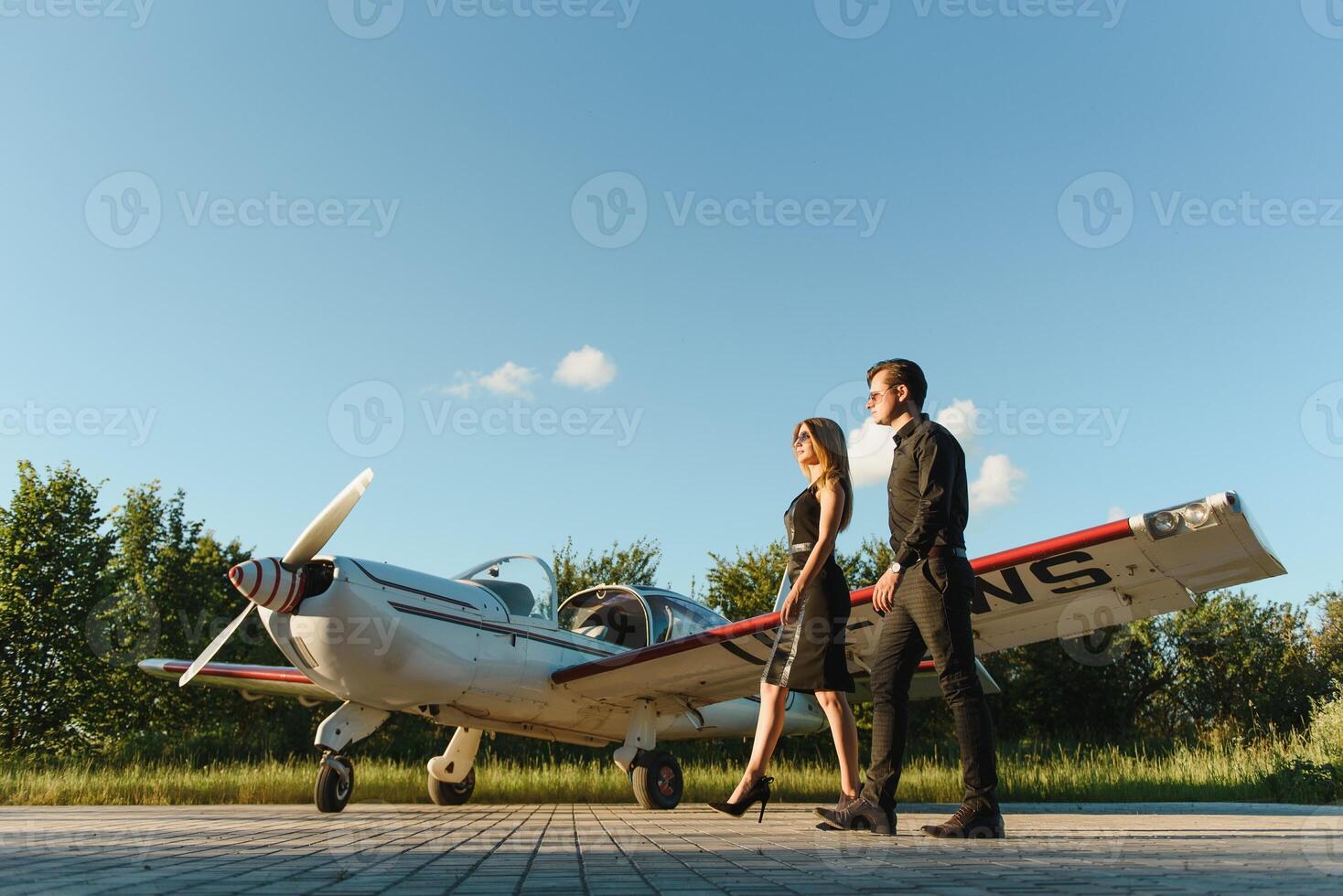 porträtt av två leende företag människor, man och kvinna, gående förbi plan hangar i flygplats fält foto